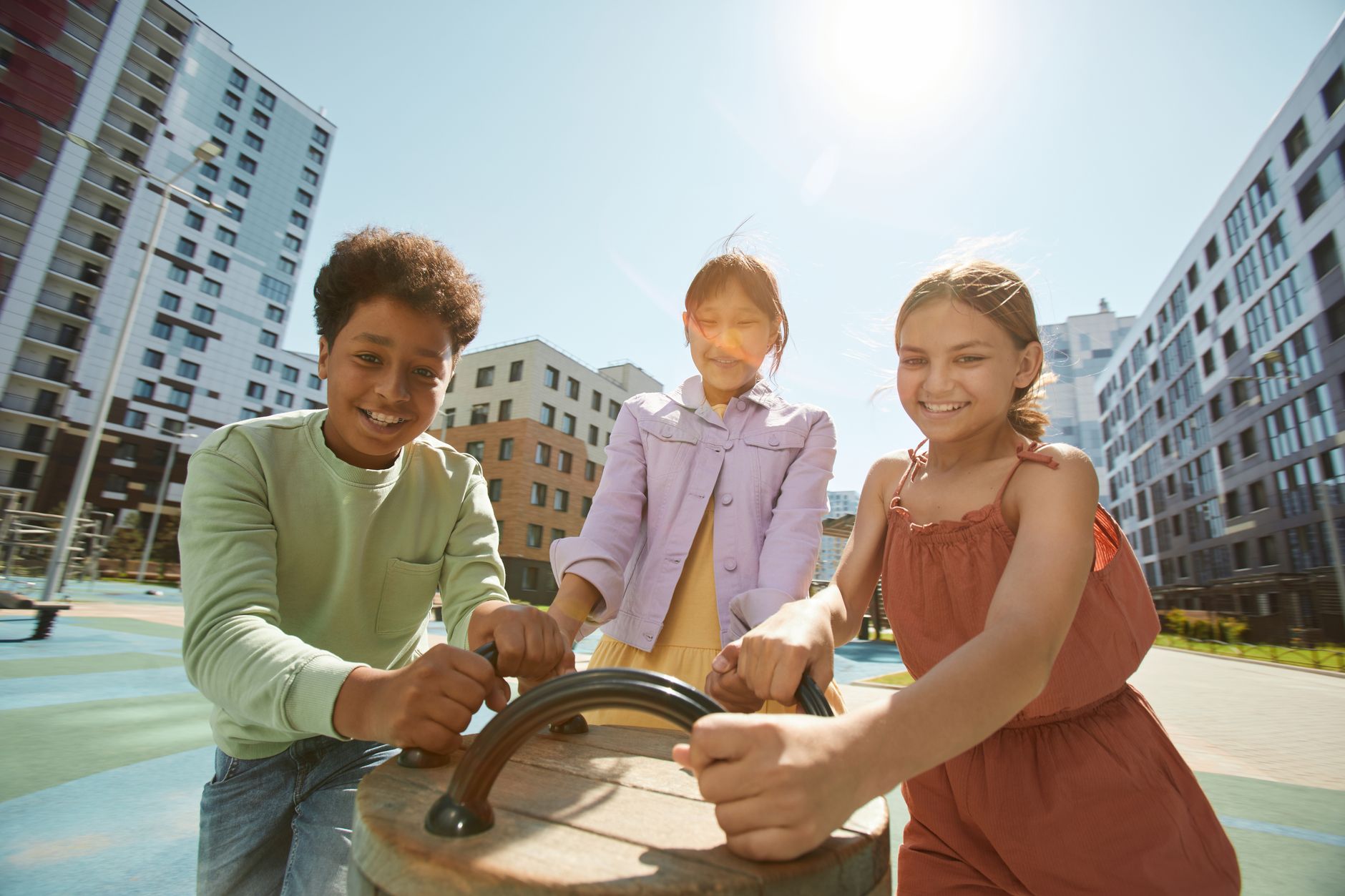 a group of kids holding on a playground equipment near buildings
